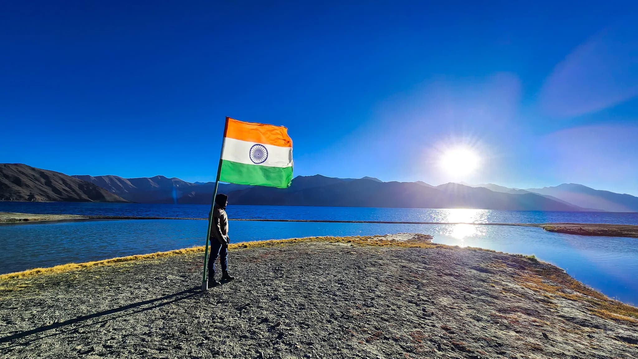 Indian flag beside Pangong Lake at sunrise in Ladakh