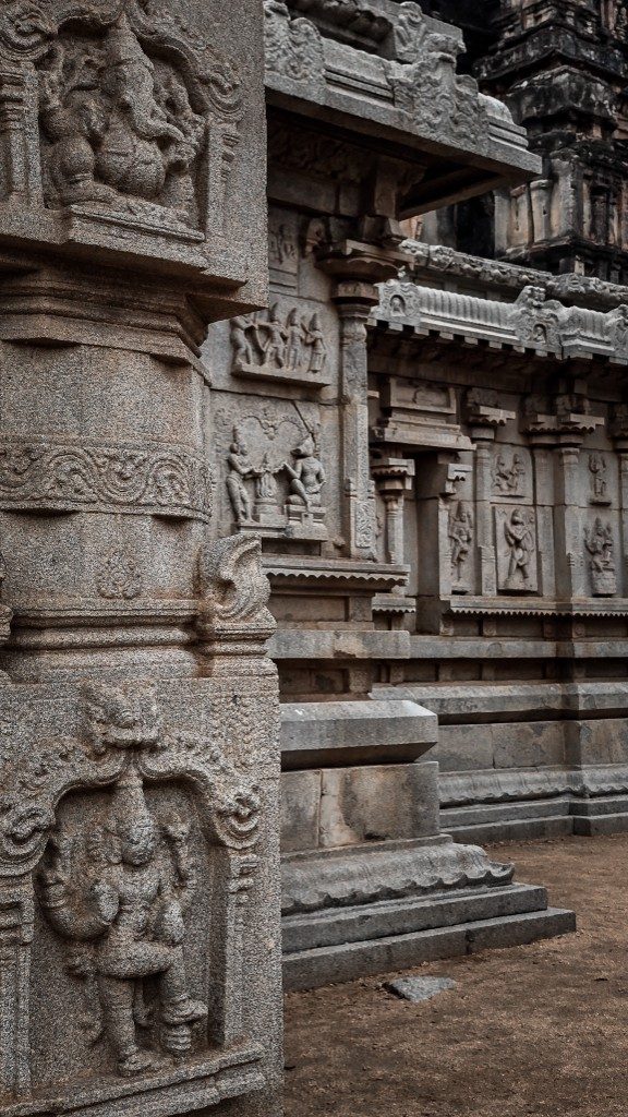 Close view of an intricately carved stone pillar at a Hampi temple — Ganesha and divine figures carved in high relief