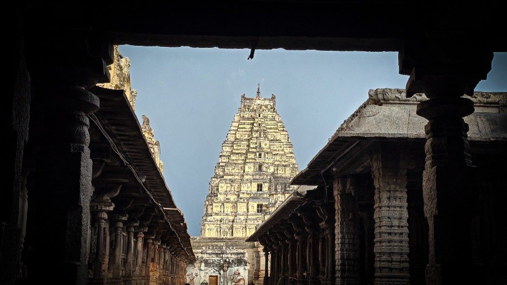 Virupaksha temple tower seen through a dark stone corridor at Hampi — a frame within a frame