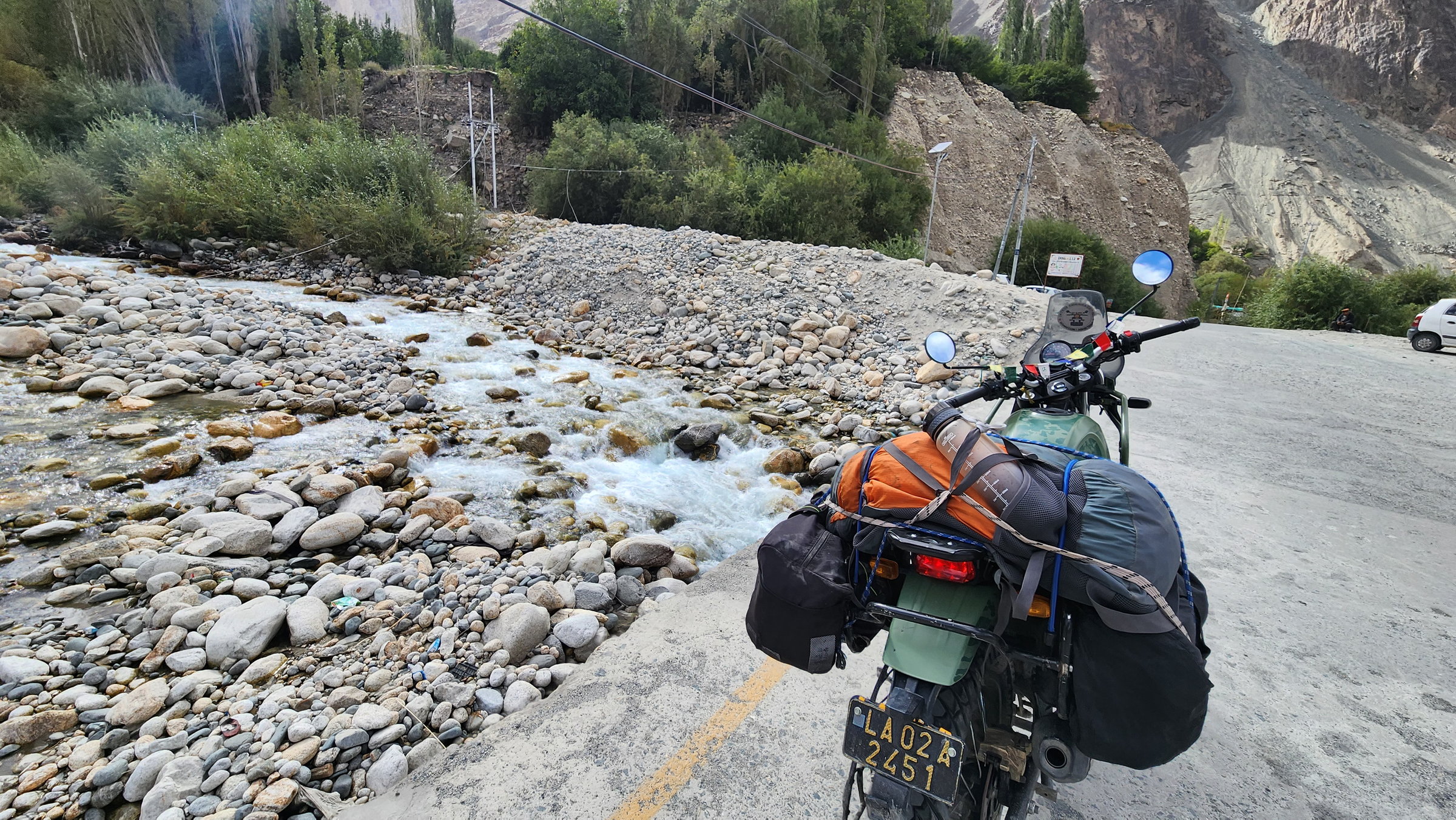 Loaded Royal Enfield Himalayan parked beside a mountain stream in Ladakh